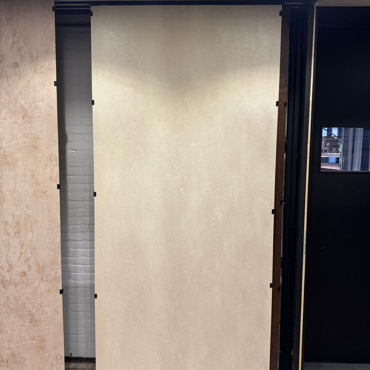 Beige betonlook SPC wandpaneel in showroom opstelling met grote plaat en strakke afwerking