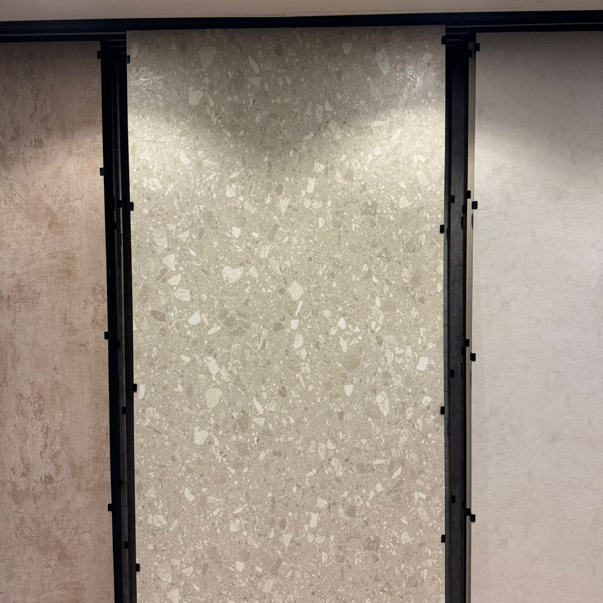Beige terrazzo SPC wandpaneel in showroom opstelling met grote plaat en lichte steenkorrels